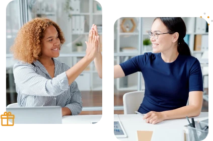 Duas mulheres sorridentes sentadas em uma mesa comemoram batendo as mãos